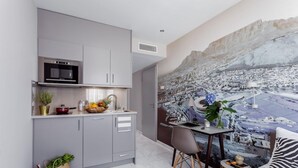 Una cocina moderna con armarios grises, horno empotrado y comedor con mesa y sillas.