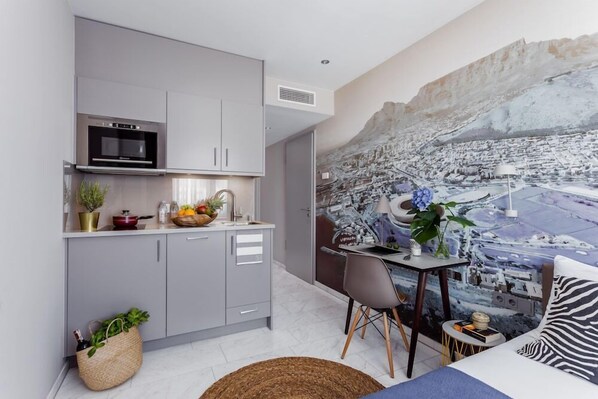 Una cocina moderna con armarios grises, horno empotrado y comedor con mesa y sillas.