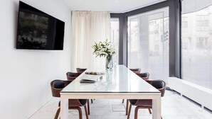A modern meeting room with a glass table, six chairs, a vase with flowers, a painting on the wall, and large windows with a city view. - Visionapartments Frankfurt Gutleutstraße (Frankfurt)