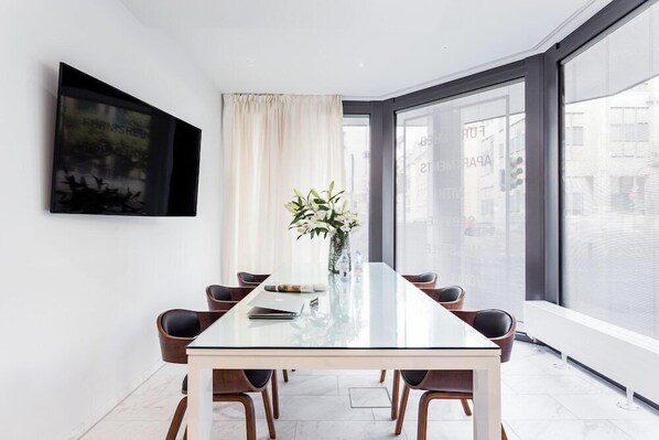 A modern meeting room with a glass table, six chairs, a vase with flowers, a painting on the wall, and large windows with a city view. - Visionapartments Frankfurt Gutleutstraße (Frankfurt)