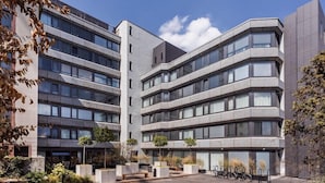 Un edificio moderno de varios pisos con un patio central que incluye macetas y una zona de aparcamiento para bicicletas.