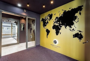 A modern interior with a large world map mural, a glass door entrance, and a sign for Vision Apartments. - Visionapartments Frankfurt Gutleutstraße (Frankfurt)