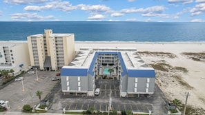 Ein Hotel mit Pool, Parkplatz und Blick auf den Strand.