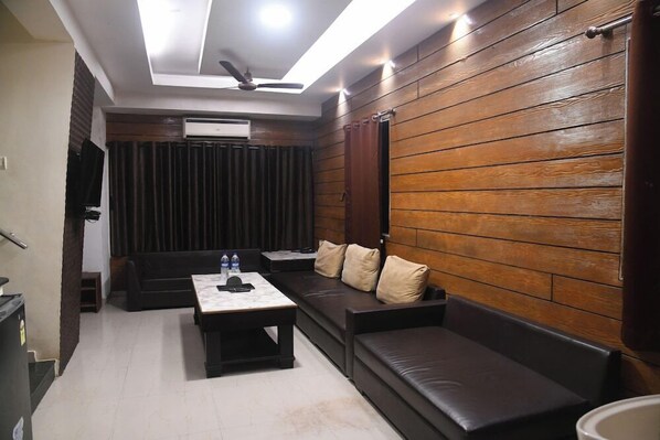 A modern living room with a sofa, a coffee table, and a ceiling fan. - Hill Forest Resort (Mawal)