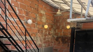 A rooftop patio with a brick wall, a round seating area, a white sofa, wicker chairs, and a staircase. - Perfect 4-bedroom house for 12 pp in Envigado/ Medellín with Jacuzzi and rooftop (Envigado)