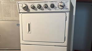 A compact, white, two-door washer and dryer unit with a front-loading design, located in a room with patterned floor tiles and a partial view of a red couch in the background. - Perfect 4-bedroom house for 12 pp in Envigado/ Medellín with Jacuzzi and rooftop (Envigado)