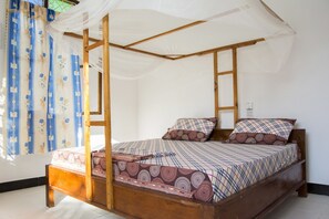 A four-poster bed with a canopy, wooden frame, and patterned bedding. - Aluna Beach Lodge (Nungwi)
