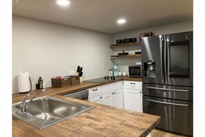 A modern kitchen with stainless steel appliances, wooden countertops, and white cabinetry. - Cozy Colorado Getaway (Colorado Springs)