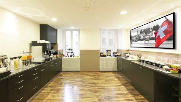 A modern kitchen with a wooden floor, black cabinets, and a large window. - Fred Guest House Zurich Hauptbahnhof (Zürich)