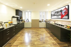 A modern kitchen with a wooden floor, black cabinets, and a large window. - Fred Guest House Zurich Hauptbahnhof (Zürich)