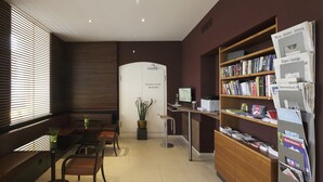 A modern library with a wooden desk, bookshelves, and a computer. - Fred Guest House Zurich Hauptbahnhof (Zürich)