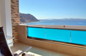 A balcony with a view of the ocean and mountains.