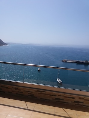 A balcony with a view of the sea and a distant coastline. - Hotel Minos (Agios Vasileios)