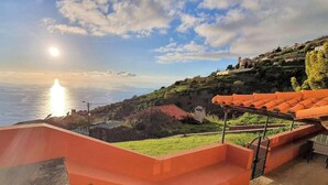 A coastal property with a view of the sea, terraced gardens, and a red-roofed structure. - Quinta São Lourenço - Casa Frente | Sunset - Pool - Seaview (FAJÃ DA OVELHA)