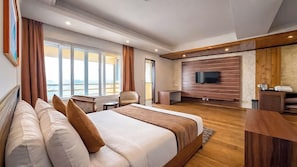 Quarto de hotel moderno com uma cama grande, televisão na parede e vista para o mar.