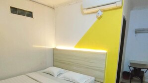 A single bed with a wooden headboard, a small bedside table, and an air conditioning unit mounted on the wall. - Sentra Hotel (Palembang)