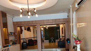 A hotel lobby with a reception desk, seating area, and a green wall with a white fence. - Sentra Hotel (Palembang)