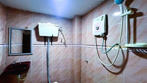 Ein Badezimmer mit Waschbecken, Spiegel, Dusche und Warmwasserbereiter.