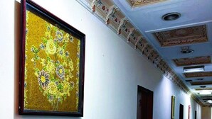 Ein Flur mit blauen und weißen Wänden, einem gerahmten Blumenbild und einer Decke mit dekorativen Stuckverzierungen.