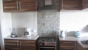 A kitchen with wooden cabinets, a stainless steel stove, a sink, a coffee maker, and a toaster. - Atlantik Sicht Sef Catering Apartment Self Catering (Swakopmund)