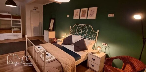 A guest room with a bunk bed, bedside tables, a chair, and artwork on the wall. - F3 Hostels (Cascais)