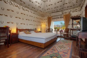 A bedroom with a wooden bed, a desk with a television, and a patterned rug. - Aaram Baagh Agra On Pachar Group (Pushkar)