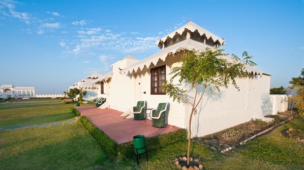 A white villa with a tiled patio, two wicker chairs, and a small tree. - Aaram Baagh Agra On Pachar Group (Pushkar)