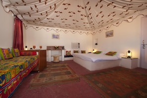 Quarto com uma cama, escrivaninha, cadeira, abajur e tapete.