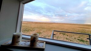 A window with a view of a flat landscape and a cloudy sky. - Skálatjörn Homestay (Selfoss)