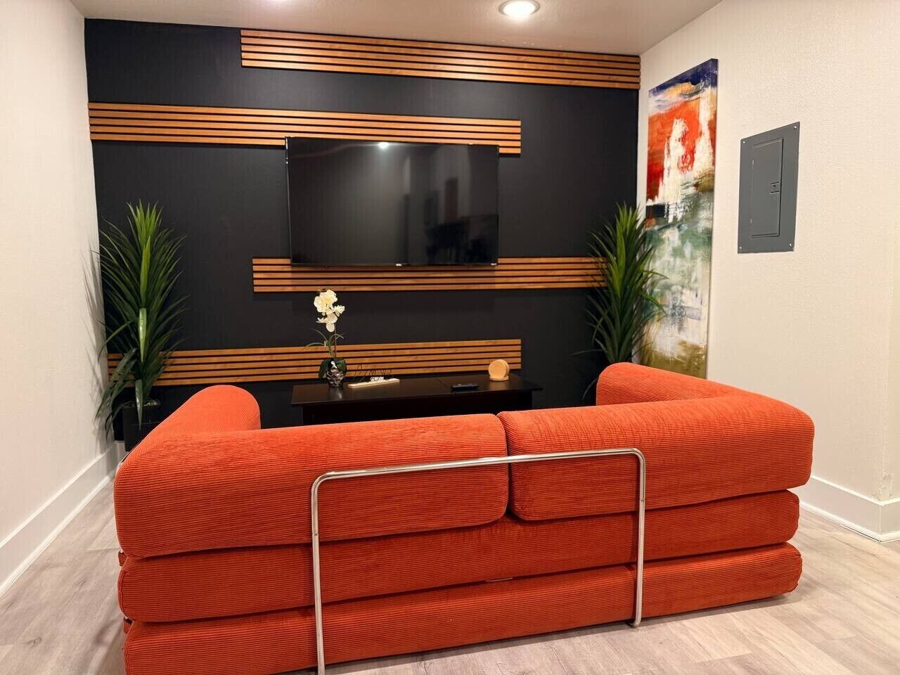 A modern living room with a sectional sofa, a flat-screen TV, and decorative wall panels.
