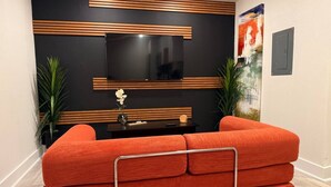 Ein modernes Wohnzimmer mit einer Eckcouch, einem Flachbildfernseher und dekorativen Wandpaneelen.