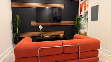 A modern living room with a sectional sofa, a flat-screen TV, and decorative wall panels.