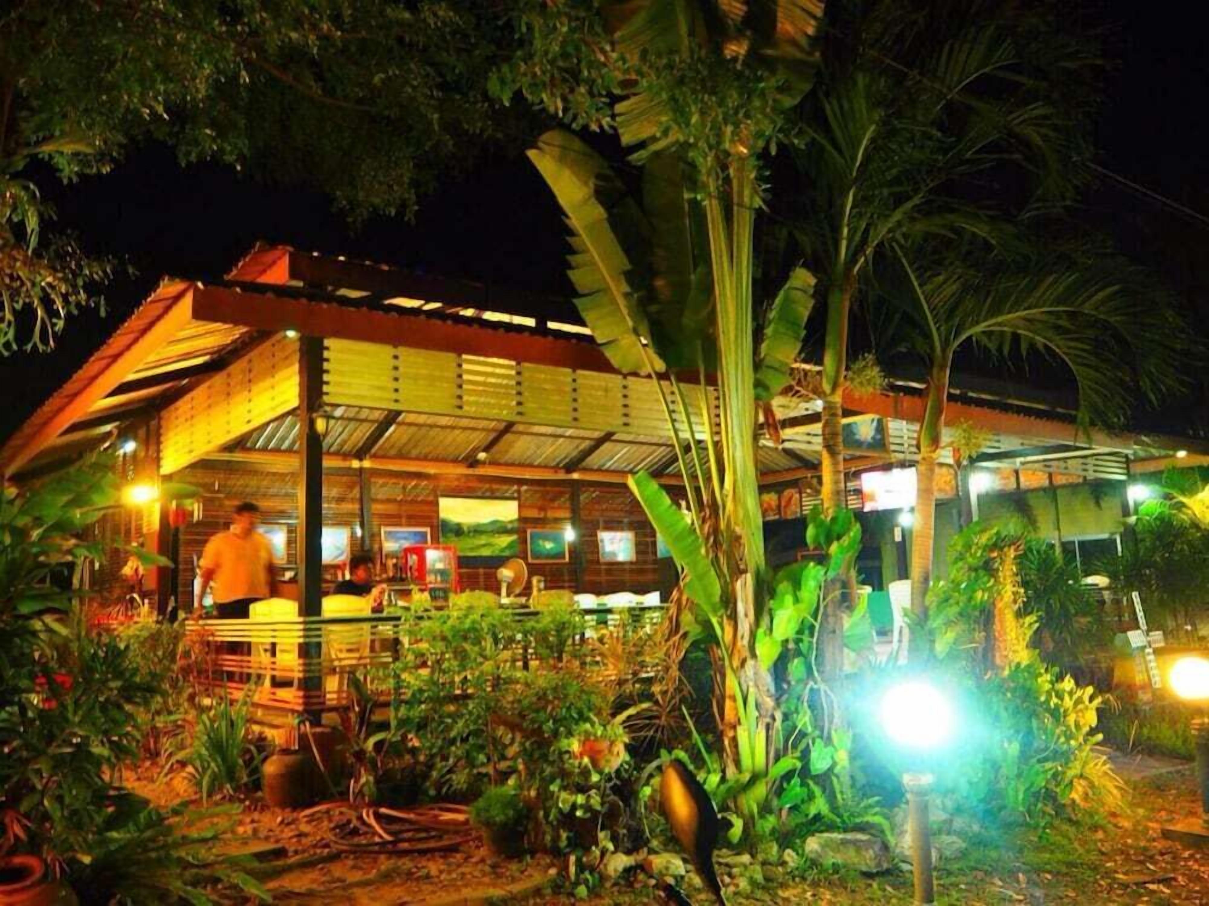 A restaurant with a covered outdoor seating area, surrounded by lush greenery and plants.