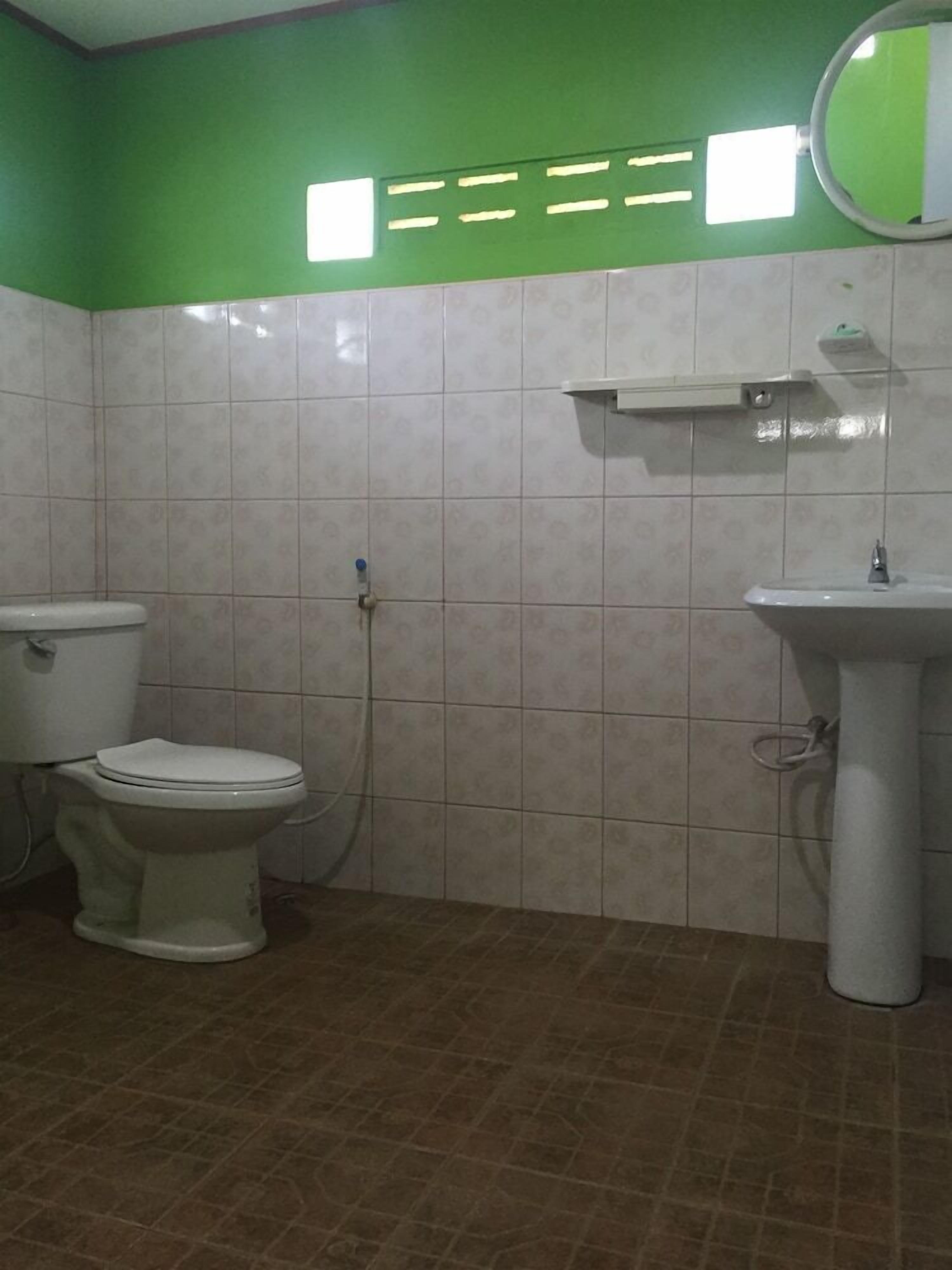 A bathroom with a toilet, sink, and green wall.