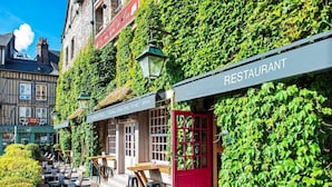Een restaurant met terras, een rode deur en een bordje dat een hotelsalon en spa aangeeft.
