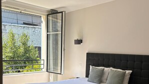 Un dormitorio con una cama grande, una ventana con vistas a la vegetación y un balcón.