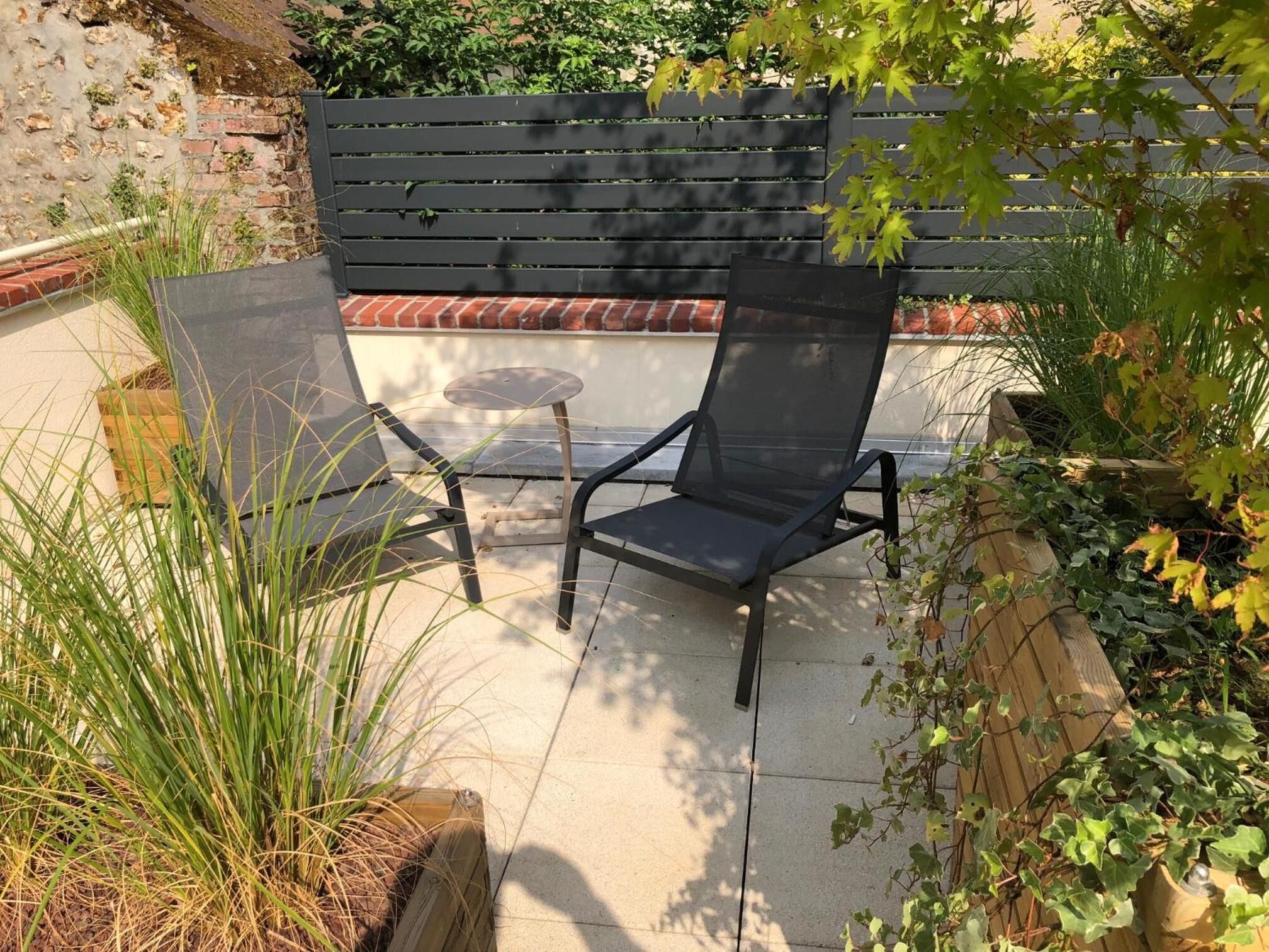 A patio area with a black metal chair and a small round table.