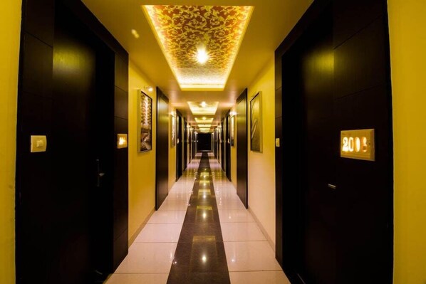 Ein Hotel-Flur mit langer Diele, Türen an beiden Seiten und einer gemusterten Decke.