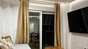 A modern bedroom with a bed, a small wooden table, and a TV mounted on the wall.