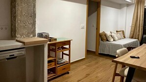 A compact living space with a kitchenette, a bed, a dining area, and a small wooden cabinet.