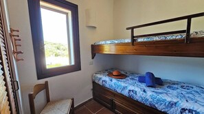 Una cama litera con ventana, una silla y una mesita.