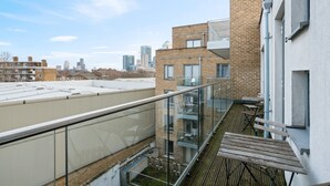 Une terrasse sur le toit dotée d’une balustrade en verre, de tables en bois et offrant une vue panoramique sur la ville.