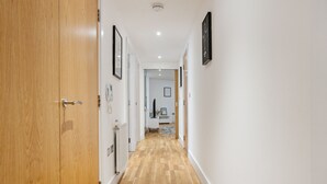 Un couloir doté d’un plancher en bois, de murs blancs et de tableaux encadrés.