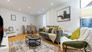 Un salon moderne avec un canapé gris, une table basse et un coin repas comprenant une table et des chaises blanches.