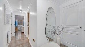 A hallway with a white door, a large mirror, and a vase with branches. - Peaceful 2BR Flat |Near Becontree Stn.|Family|ST (Greater London)