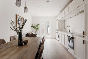 Una cocina moderna con una mesa de comedor de madera, armarios blancos y un amplio ventanal.