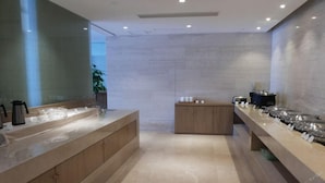 A modern bathroom with a large bathtub, a wooden vanity, and a countertop with various toiletries. - Ji Hotel (Shanghai)