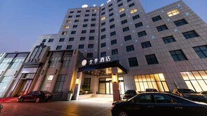 A multi-story hotel with a modern design, featuring a prominent entrance with illuminated signage. - Ji Hotel (Shanghai)