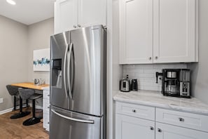 A modern kitchen with a stainless steel refrigerator, white cabinets, a wooden countertop, and a coffee maker. - 2BR Home w/ Fenced Backyard, Minutes to Uptown (Charlotte)