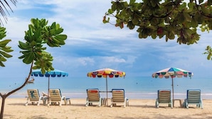 Une plage avec des chaises longues et des parasols.